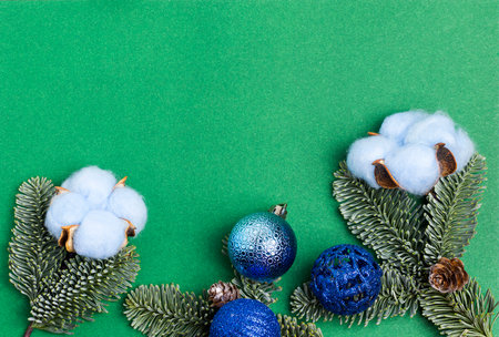 Green background with cotton, fir branches and Christmas balls.の写真素材