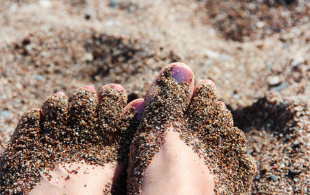Women's feet in the sea sand. Dirty feet.の写真素材