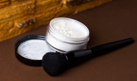 Matte white face powder with a black brush. A jar of powder on a brown background.