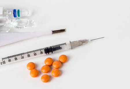 Orange pills with syringe and ampoules on a white background.の写真素材