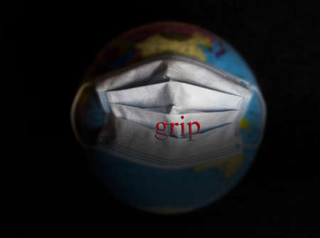 Globe in a medical mask. Planet Earth. Globe. On the mask there is an inscription grip.の写真素材