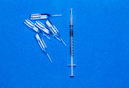 Medical syringe with ampoules on a blue textured background.の写真素材