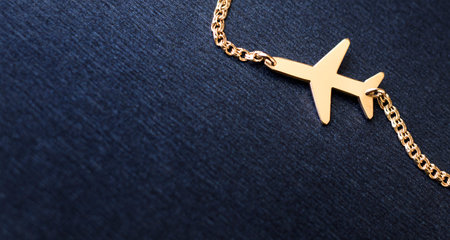 Gold plane on a chain on a blue background.の写真素材