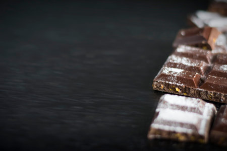 Pieces of chocolate in powdered sugar on a black background.の写真素材