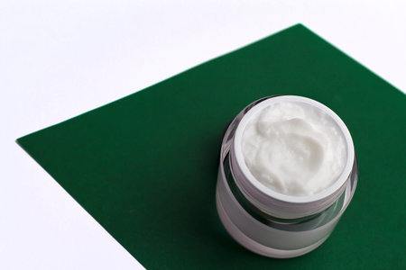 Container with cream on a green background.