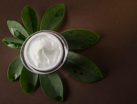 Jar with a hair mask on a brown background with a plant.の写真素材