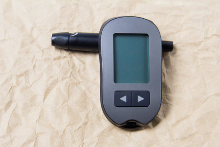 A device that measures blood sugar. Glucometer with a needle on a crumpled background.