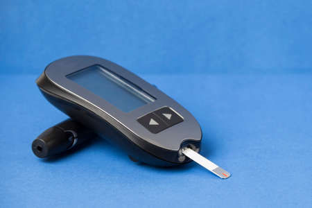 Glucometer with a needle on a blue background. Measurement of blood glucose.の写真素材
