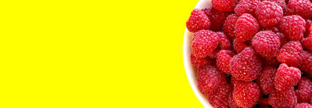 Raspberries in a bowl on a yellow background.の写真素材