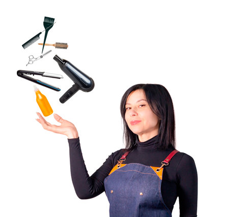 Woman hairdresser in apron holding hairbrush and scissors, isolated on white backgroundの写真素材
