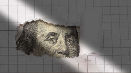 Benjamin Franklin peers through torn white paper. concept.の写真素材