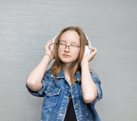 A girl in white headphones listens to music.の写真素材