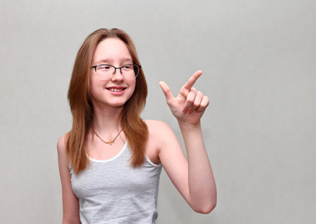 A girl in a T-shirt points to the right with her finger.の写真素材