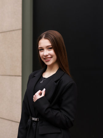 Brunette girl in a black jacket on a black background.の写真素材