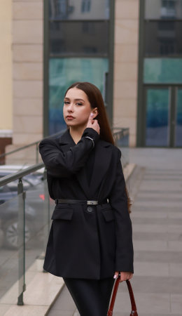 A girl in a black jacket with a belt against the background of the city.の写真素材