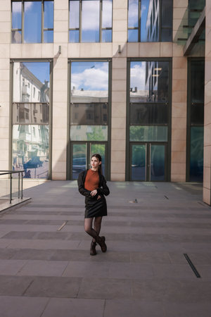 A girl with freckles in a leather skirt near a skyscraper.の写真素材