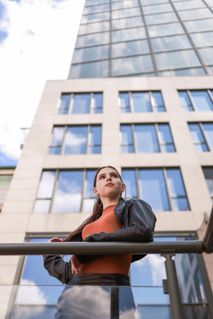 A girl with freckles in a leather skirt near a skyscraper.の写真素材