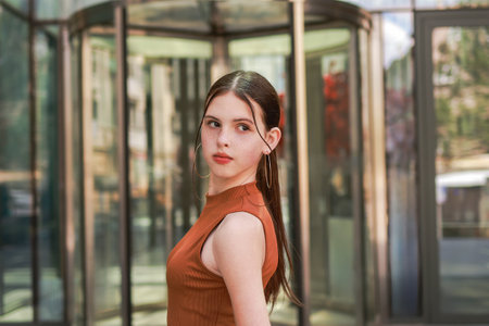 A girl with freckles in a leather skirt near a skyscraper.の写真素材