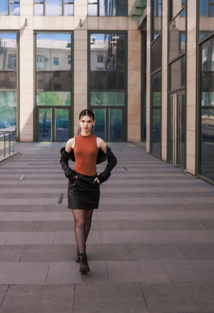 A girl with freckles in a leather skirt near a skyscraper.の写真素材