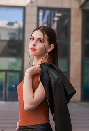 A girl with freckles in a leather skirt near a skyscraper.の写真素材