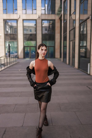 A girl with freckles in a leather skirt near a skyscraper.の写真素材