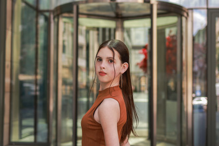 A girl with freckles in a leather skirt near a skyscraper.の写真素材