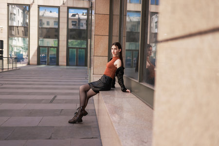 A girl with freckles in a leather skirt near a skyscraper.の写真素材