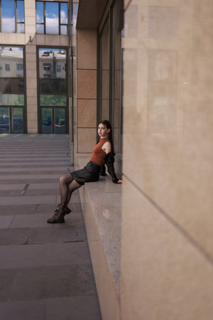 A girl with freckles in a leather skirt near a skyscraper.の写真素材