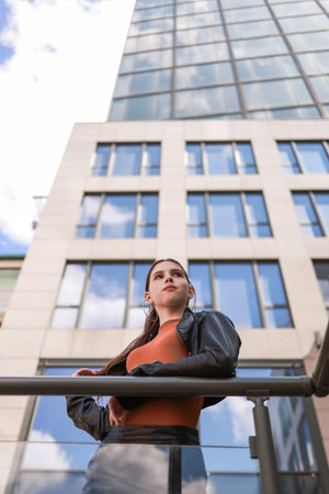 A girl with freckles in a leather skirt near a skyscraper.の写真素材