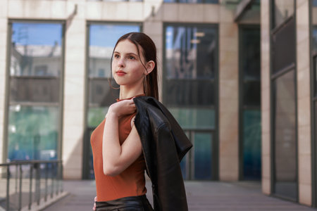 A girl with freckles in a leather skirt near a skyscraper.の写真素材
