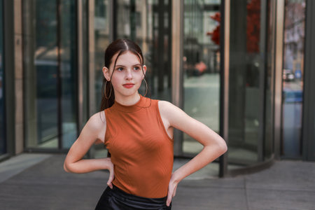 A girl with freckles in a leather skirt near a skyscraper.の写真素材