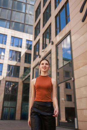 A girl with freckles in a leather skirt near a skyscraper.の写真素材