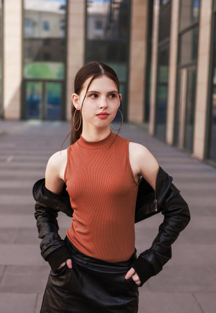 A girl with freckles in a leather skirt near a skyscraper.の写真素材
