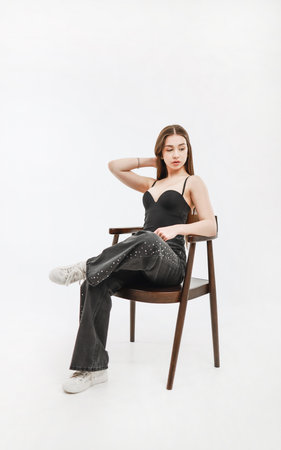 A girl in gray jeans is sitting on a chair.の写真素材