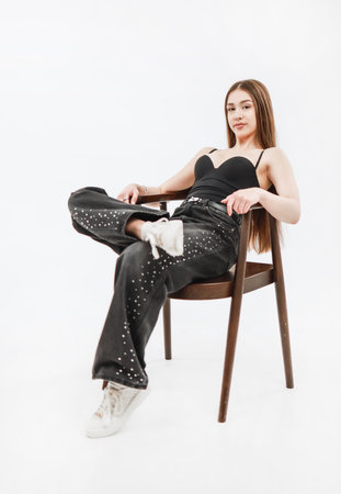 A girl in gray jeans is sitting on a chair.の写真素材