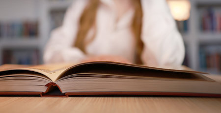 There is a thick book on the table near the girl.の写真素材