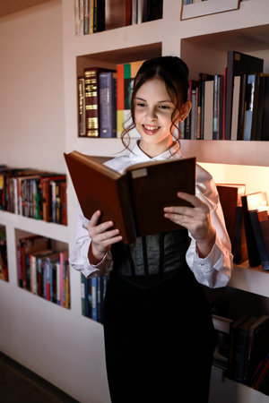 Happy girl with a book in the library.の写真素材