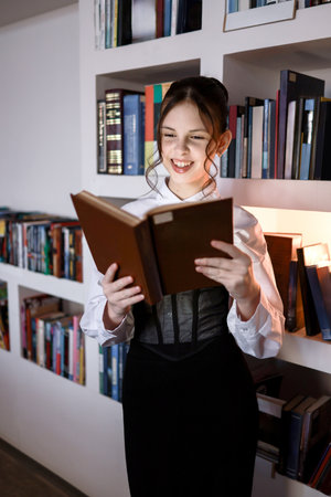 Happy girl with a book in the library.の写真素材
