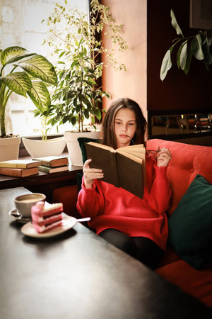 The girl is reading a book and drinking coffee in a cozy atmosphere.の写真素材