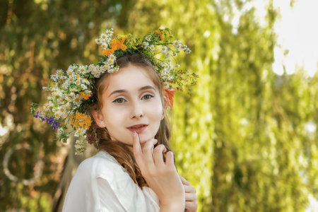 Girl in a wreath against the background of a river at sunset.の写真素材