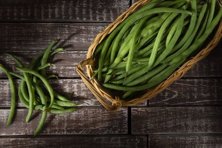Round beans in a wicker basket, on a wooden background, in a dark environmentの写真素材