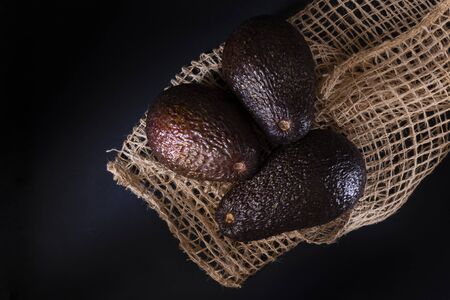 Three avocados and a sack of fique. all in black backgroundの写真素材