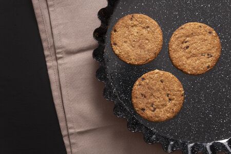 Oatmeal cookies and chocolate chips on black backgroundの写真素材