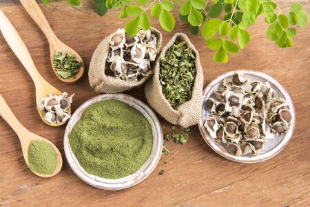Moringa, hojas, semillas, polvo sobre un fondo de madera - Moringa oleiferaの写真素材