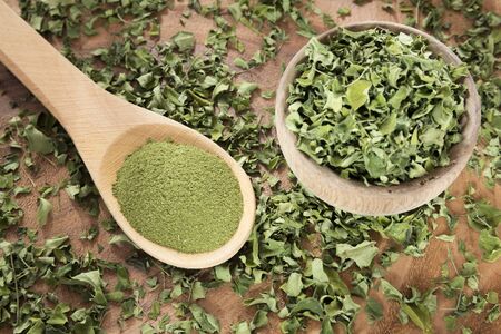 Wooden spoon and dehydrated moringa leaves, on a wooden background - Moringa oleiferaの写真素材