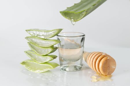 sliced aloe vera leaves and honey-pot grinder on white backgroundの写真素材