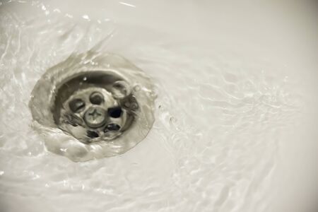 water flow into drain in white bathの写真素材
