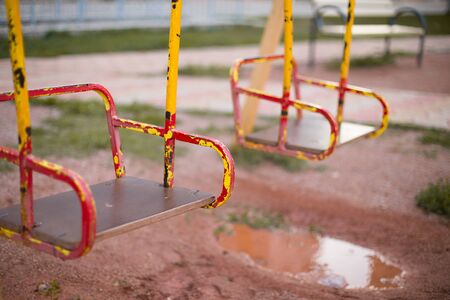 Bright, new beautiful swing on the Playground in the yard and a puddle.の写真素材