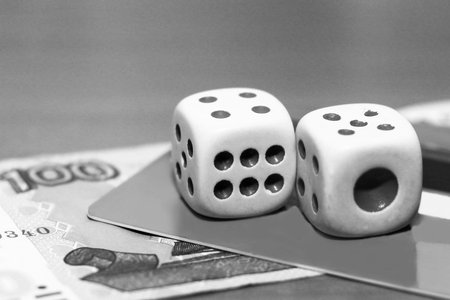 Two dice laying over a pile of money, finance