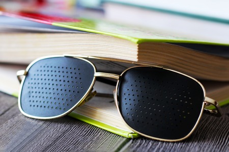 Black medical glasses with holes and booksの写真素材